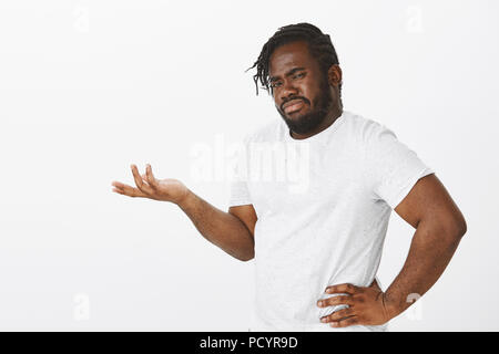 Kerl nicht Idee erhalten. Portrait von Befragten gestört afrikanische Mann mit Bart, stehend die Hälfte - gedreht mit der Hand auf der Hüfte und Palm in Frage gest Stockfoto