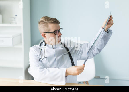 Junge kaukasier Arzt sitzt in seinem Büro und suchen X-ray Image Stockfoto