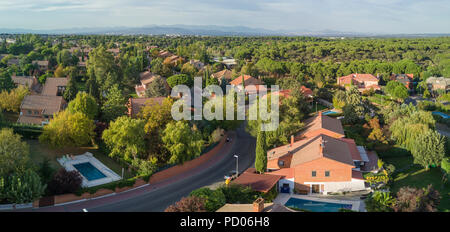 Ein Luftbild von der Drohne einer Nachbarschaft in einem Wald am Stadtrand von Madrid Stadt, die auf den weiten Horizont mit seinen Skyline gesehen werden kann. Stockfoto