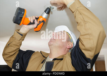 Man bohrt Löcher in Betondecke mit Bohrmaschine Stockfoto