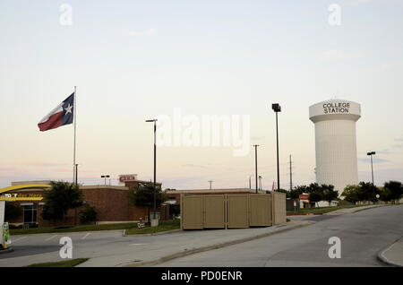 Texas Flagge im Wind mit einem Wasserturm Kaution lesen College Station, in College Station, Texas, United States. Stockfoto