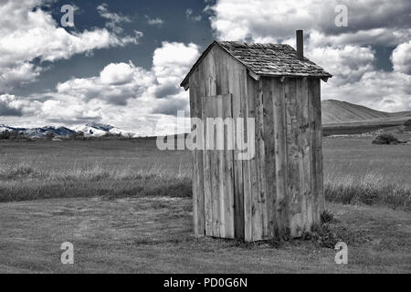 Ein rustikales Plumpsklo sitzt auf Ackerland in ländlichen Chesterfield, Idaho. Original Bild ist entsättigt, abgesehen von den blauen Himmel, für Künstlerische Wirkung. Stockfoto