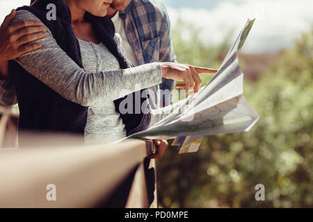 Frau zeigt auf die Karte beim Stehen mit ihrem Freund. Auf der Suche nach Reiseziel auf der Karte. Stockfoto