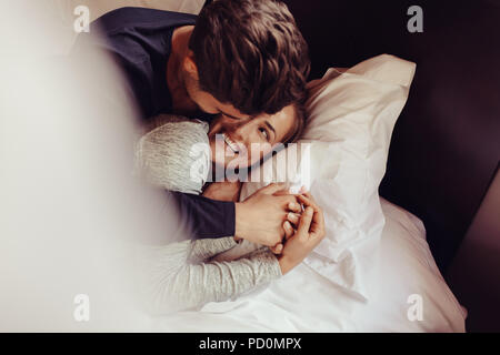 Romantische junge Paar in Liebe liegend auf dem Bett. Schönes Paar im Bett mit einem Lächeln. Stockfoto