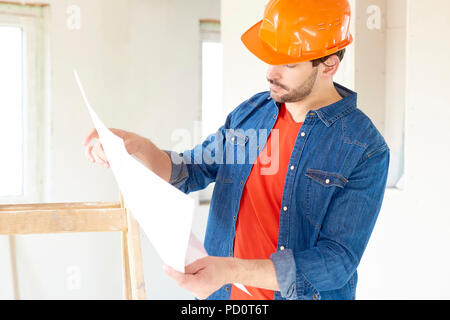 Portrait von jungen männlichen Ingenieur holding Blaupause in seiner Hand, während bei Bauunternehmen hat sich Website. Stockfoto