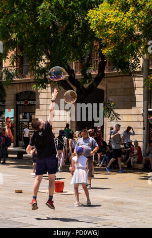 Kinder spielen mit Seifenblasen, die durch eine Straße Performer in der Plaza, Avinguda Catedral, 5, Barcelona, Spanien Stockfoto