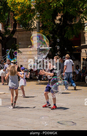 Kinder spielen mit Seifenblasen, die durch eine Straße Performer in der Plaza, Avinguda Catedral, 5, Barcelona, Spanien Stockfoto