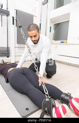 Persönlichen Ausbilder anzeigen Frau wie am Cable Crossover machine im Fitnessstudio zu trainieren Stockfoto