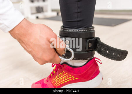 Nahaufnahme von Hand schneiden Link zu Ankle Strap der jungen Frau mit bunten Laufschuh in der Turnhalle Stockfoto