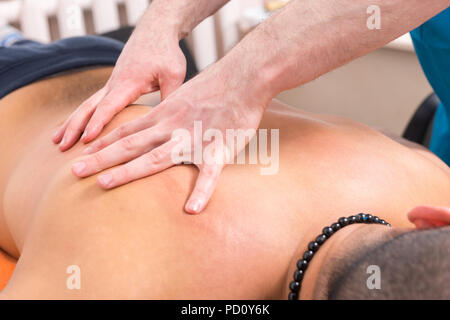 Nahaufnahme Detail der männlichen Masseur Hände geben Zurück Rub auf Nicht identifizierbare männlichen Klienten liegen auf Magen Stockfoto