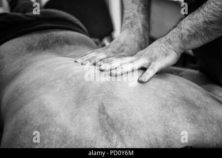 Schwarze und Weiße Nahaufnahme Detail der männlichen Masseur Hände geben Zurück Rub auf Nicht identifizierbare männlichen Klienten liegen auf Magen Stockfoto