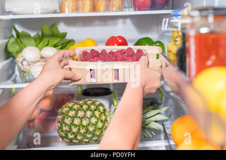 Person, Korb mit frischen Himbeeren aus offenen Kühlschrank Stockfoto