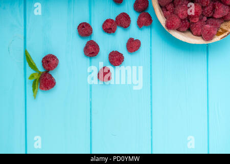 Platte von Reifen Himbeeren mit dem verschütteten Obst über einem blauen Holz- Hintergrund mit Kopie Raum von oben gesehen Stockfoto