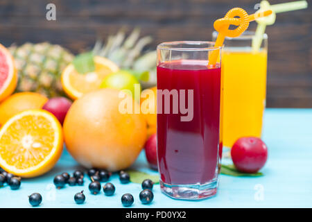 Zwei Gläser aus frisch gepresstem Saft mit verschiedenen tropischen Früchten und Beeren auf einem blauen Tisch in einer gesunden Diät Konzept Stockfoto