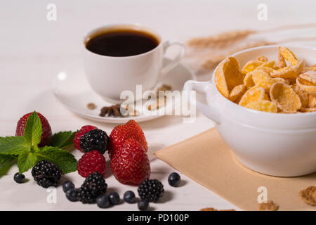 Vielzahl von frischen Beeren und eine Schüssel mit kommerziellen Müsli zum Frühstück mit starken schwarzen Kaffee in der Nähe zu sehen, serviert. Stockfoto