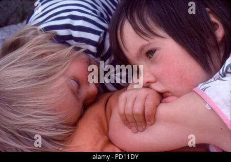 Blick über 5 Jahre altes Mädchen Kind Kinder Freunde tagträumen oder gelangweilt Schmollen nebeneinander liegend zum Kleinkind im Sommer Urlaub in den 70er 70er Jahre Großbritannien BRITISCHES KATHY DEWITT Stockfoto