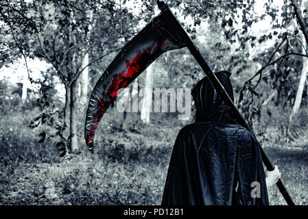 Rückansicht des Daemon Hexe mit Reaper und Blut in das Geheimnis Wald. Horror und Ghost Konzept. Halloween Tag und Unheimlichen Szene Thema. Stockfoto