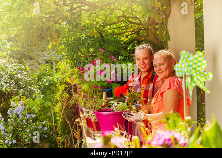 Zwei glückliche Mädchen im Teenageralter Blumen Pflanzen im Freien Stockfoto