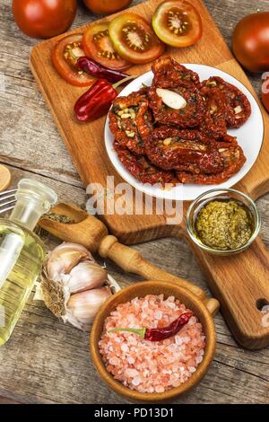 Getrocknete Tomaten mariniert in Olivenöl mit Knoblauch. Sonnenblumenkerne mit Tomaten auf einem alten Holztisch Stockfoto