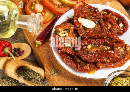 Getrocknete Tomaten mariniert in Olivenöl mit Knoblauch. Sonnenblumenkerne mit Tomaten auf einem alten Holztisch Stockfoto