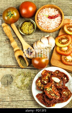 Getrocknete Tomaten mariniert in Olivenöl mit Knoblauch. Sonnenblumenkerne mit Tomaten auf einem alten Holztisch Stockfoto