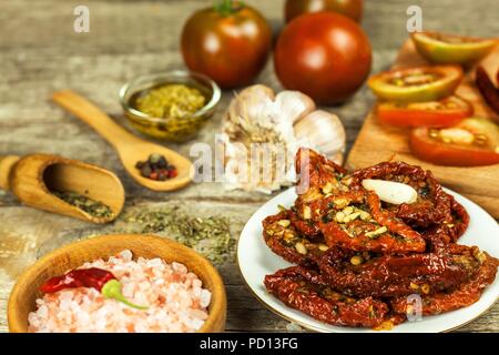 Getrocknete Tomaten mariniert in Olivenöl mit Knoblauch. Sonnenblumenkerne mit Tomaten auf einem alten Holztisch Stockfoto