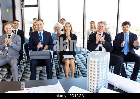 Publikum applaudieren, Geschäftsleute und Investoren bei der Präsentation Zimmer sitzen, Konferenzsaal, Ansicht vom Lautsprecher Tabelle mit Dokumenten, Modell der m Stockfoto