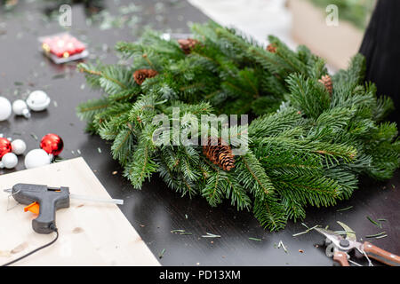 Hersteller von Weihnachten Kranz aus Zweigen von Pinien für Urlaub. Master Class auf dem Bilden der dekorativen Ornamenten. Weihnachten Einrichtung mit Ihren eigenen Händen. Das neue Jahr feiern. Flower Shop Stockfoto