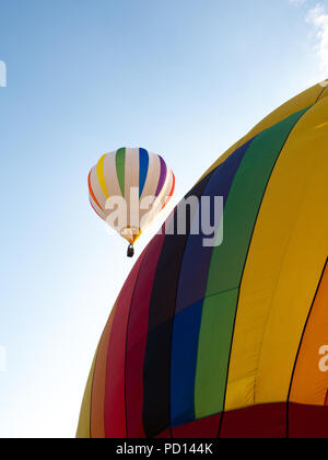 Zwei Heißluftballons mit einem im Flug und einem Aufgeblähten aber Schreibwaren im Vordergrund. Stockfoto