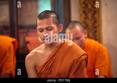 Ein junger buddhistischer Mönch singen mit seinen Augen während einer Zeremonie in einem der Tempel in ihrem Kloster geschlossen. Stockfoto