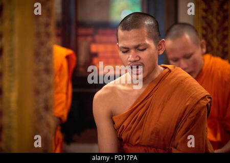 Ein junger buddhistischer Mönch singen mit seinen Augen während einer Zeremonie in einem der Tempel in ihrem Kloster geschlossen. Stockfoto