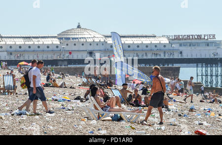 Brighton, Großbritannien - 5 August 2018 die Sonnenanbeter unter den Müll auf Brighton Beach am Morgen nach der jährlichen Pride Parade und Party. Es wird geschätzt über 250000 Menschen die Parade und Britney Spears Konzert am Samstag sorgte aber kämpfte, um nach Hause zu kommen, weil der Bahnhof hatte aus Gründen der Sicherheit aufgrund der Zahlen, die versuchen, die Züge zu fangen, geschlossen zu werden. Foto von Simon Dack Stockfoto