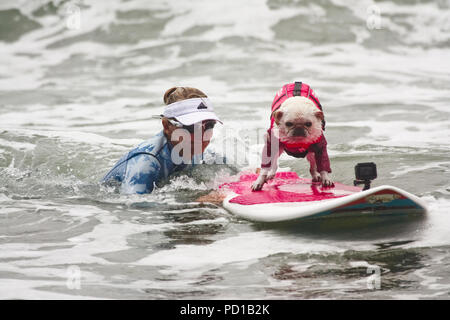 Pacifica, USA. 04 Aug, 2018. Alecia Nelson drückt ihr Hund gidget auf dem Surfbrett. Zahlreiche große und kleine Hunde in der 'World Dog Surfen Meisterschaften teilgenommen" in der Nähe von San Francisco. Quelle: Barbara Munker/dpa/Alamy leben Nachrichten Stockfoto