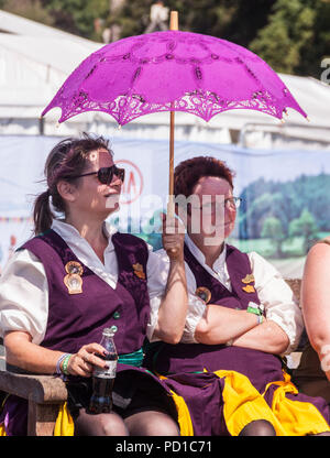 Sidmouth, Großbritannien 5. Aug 18 Verstopfen Tänzer warten ihre Umdrehung in Sidmouth Folk Festival Off unter einem Sonnenschirm kühlen die Temperaturen wieder auf dem Devon Coast anzusteigen. Foto Central/Alamy leben Nachrichten Stockfoto