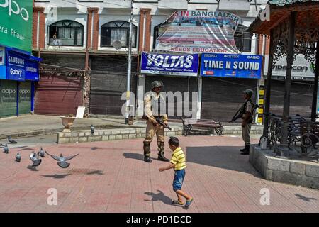 Srinagar, Indien. 5. August 2018. Ein Junge an einer Indischen paramilitärischen trooper während der Abschaltung. Leben im Kaschmir-tal kam zum Stillstand aufgrund einer vollständigen Abschaltung gemäß der Gemeinsamen Widerstand Führung (JRL) gegen die rechtliche Herausforderung in das Oberste Gericht über die Gültigkeit von Artikel 35 -, die die Menschen Bars außerhalb von Jammu und Kaschmir vom Erwerb von Immobilienbesitz im Staat. Händler Sie am historischen Uhrturm in Lal Chowk '' rechtliche Ansturm'' auf der Artikel 35 - A. Protest Demonstranten Plakate tragen, rief pro-freiheit Slogans und warne Gutschrift: Stockfoto