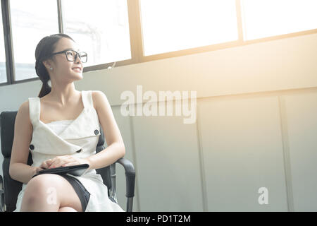 Young Business Frau in weißem Kleid Wer ist Kandidat sitzen warten, Interview, während aus großen Fenster suchen. Stockfoto