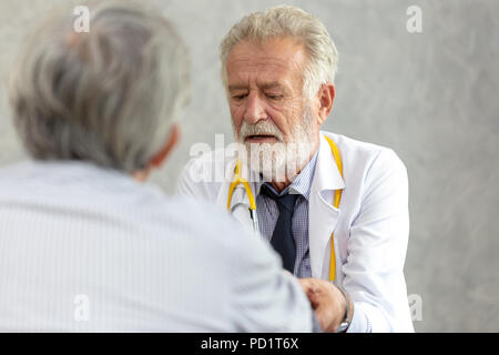 Leitender Arzt oder Leiter der Arzt, der eine Konsultation zu ihren männlichen Patienten und erläutert medizinische Informationen und Diagnose in der Klinik oder Hos Stockfoto