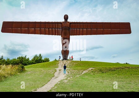 Eine Gruppe von Menschen am Fuße des massiven Engel des Nordens Skulptur von Anthony Gormley in Gateshead mit Skala Stockfoto