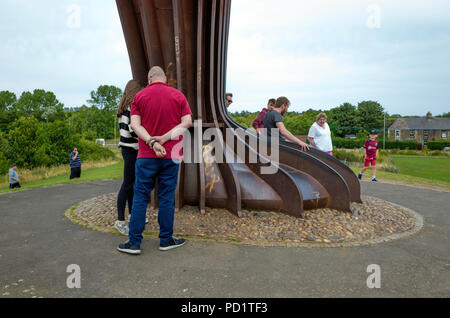 Eine Gruppe von Menschen am Fuße des massiven Engel des Nordens Skulptur von Anthony Gormley in Gateshead mit Skala Stockfoto