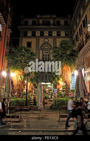 Kleiner Platz mit Palmen und einer erhöhten Clock von hohen Wohngebäuden in Neapel, Italien eingeschlossen, während der Nacht Stockfoto