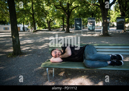 Armen Obdachlosen schlafen auf der Holzbank im Park Stockfoto