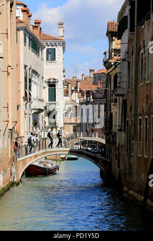 Touristen mit Rucksäcken über eine kleine Brücke in Venedig, Italien Stockfoto