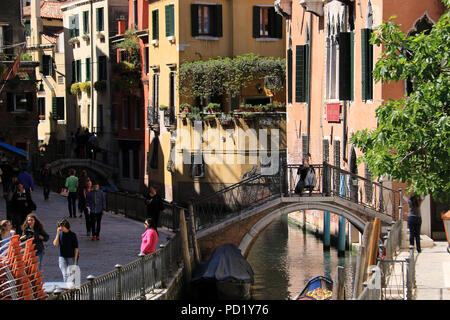 Viele Touristen durch die Stadt bummeln, während eine Person ein Bild mit seinem Handy auf einer kleinen Brücke in Venedig, Italien Stockfoto