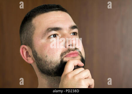 Portrait von gut aussehenden Bärtigen zuversichtlich intelligente moderne fotogene junge Mann mit kurzen Haarschnitt und schwarzen Augen auf nachdenklich Zukunft verschwommen Stockfoto