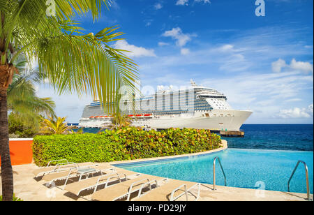 Blick vom Pool im Tropical Resort auf Kreuzfahrt Schiff angedockt am Port Stockfoto