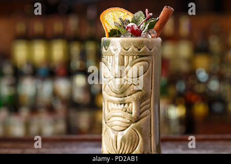 Erfrischende alkoholische Sommer Cocktail in Tiki Glas ist in der Bar im Restaurant auf einem verschwommenen Hintergrund von Alkohol. Platz für das Schreiben von Text Stockfoto