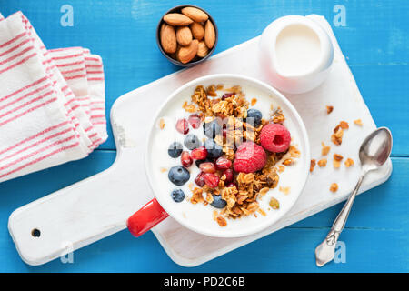 Müsli mit Joghurt, Blaubeeren, Himbeeren und Granatapfel Samen in eine Schüssel, Ansicht von oben. Gesunde Ernährung, gesunde Lebensweise, gesunde Frühstück essen Stockfoto