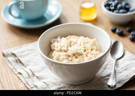 Haferflocken Porridge, schottische Hafer in eine Schüssel auf dem Tisch, Geschirrtücher. Gesundes Frühstück, gesunden Lebensstil Konzept Stockfoto