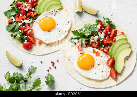 Fladenbrot Tortilla mit Avocado, Salsa und Ei auf konkreten Hintergrund. Gesundes Frühstück, Mittag- oder Abendessen. Stockfoto