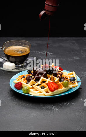 Foto Tasse schwarzen Kaffee mit Zucker mit Wiener Waffeln mit Erdbeeren, Himbeeren, Stachelbeeren und Schokolade Stockfoto